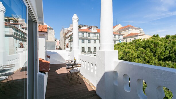 A balcony with a wooden floor, white railing, and a table with chairs.