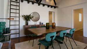 A dining area with a wooden table, teal chairs, and a mirror on the wall.