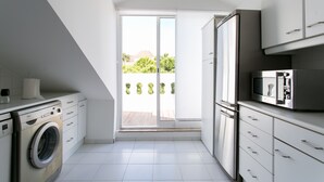 A modern kitchen with a washing machine, a microwave, and a sliding glass door leading to a balcony.