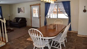 A dining area with a wooden table and white chairs, a sofa, and a chandelier. - The Ranch House Retreat (Alton)