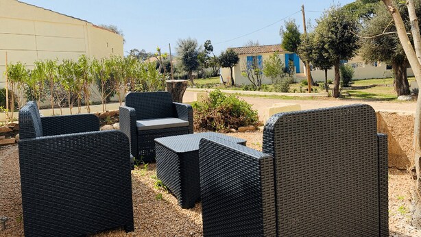 Gartenmöbel aus Rattan im Freien, mit einem Gebäude im Hintergrund.