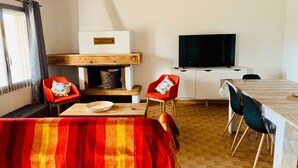 Ein gemütliches Zimmer mit Kamin, Fernseher und Essbereich.