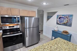 Una cocina con electrodomésticos de acero inoxidable, armarios de madera y encimera de granito.