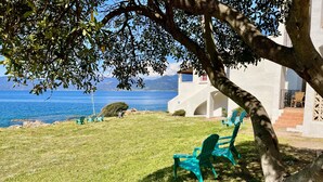 A grassy area with green chairs and a white building with steps leading to a balcony. - 4-person apartment in the heart of the pevani estate (CALCATOGGIO)