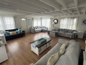 A spacious living room with a sectional sofa, a coffee table, and a fireplace. - Fire Island Beach Haven (Ocean Beach)