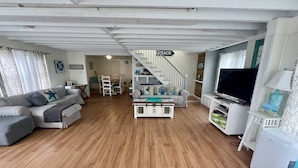 Ein geräumiger Wohnbereich mit Treppe, einem Esstisch und einem Fernseher.
