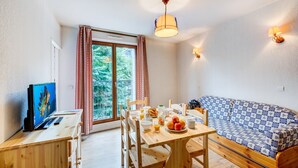 Una habitación acogedora con un escritorio de madera, una mesa de comedor, un sofá y un amplio ventanal con cortinas.