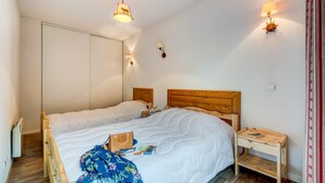 Un dormitorio con dos camas, cabeceros de madera, mesitas de noche y lámparas de pared.