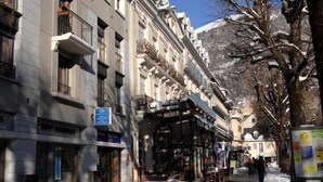 Una calle nevada con edificios históricos, incluido un hotel con un letrero que dice 'Hotel de Ville'.