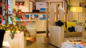 A hotel reception area with wooden furniture, a reception desk, and a map on the wall.