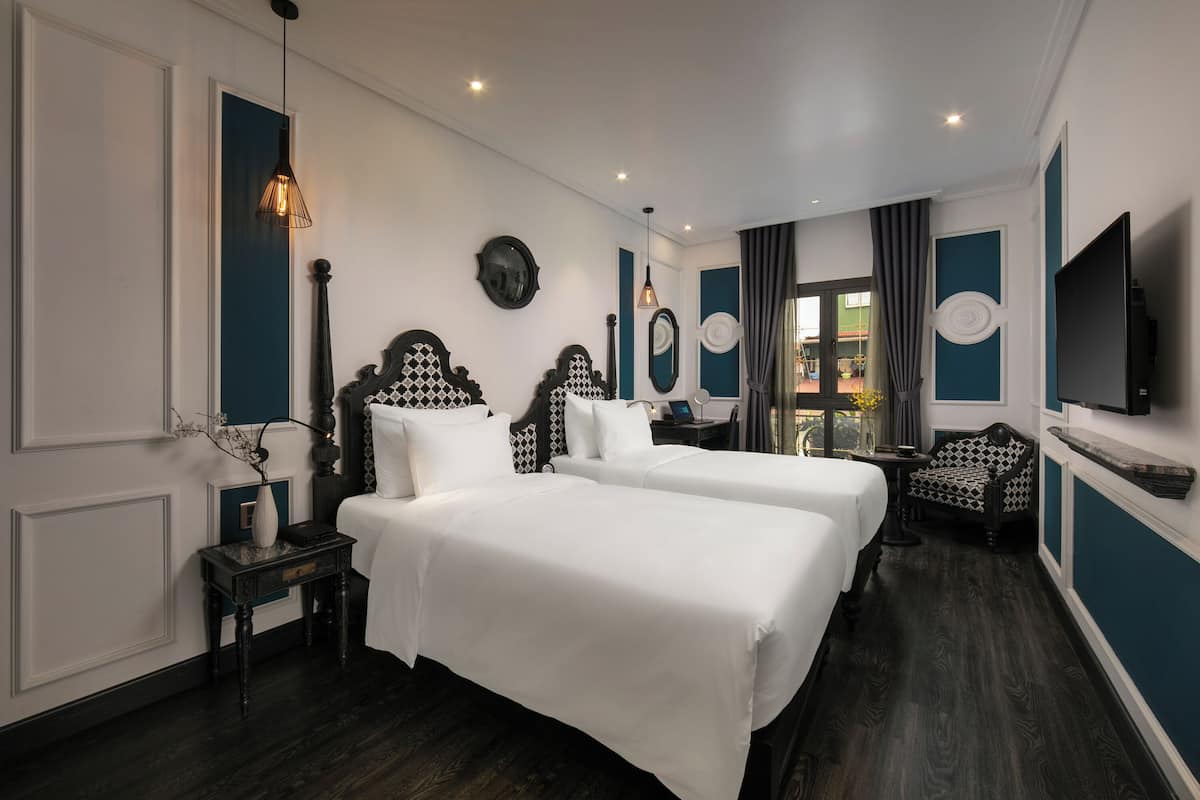 A hotel room with two beds, a TV, a chair, and a view of the outside.