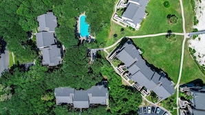 An aerial view of a residential area with multiple houses, a swimming pool, and well-maintained lawns.