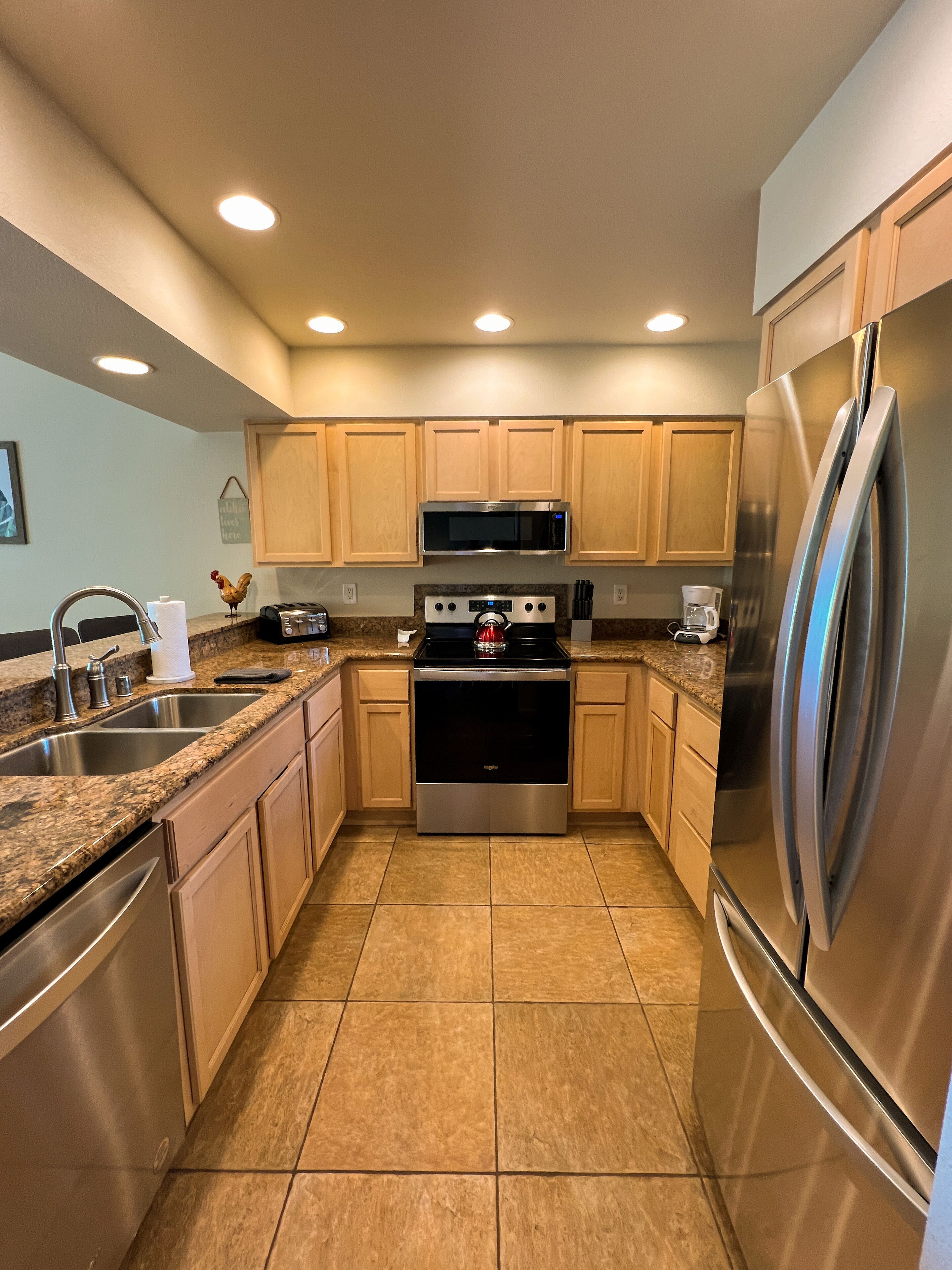 A modern kitchen with granite countertops, stainless steel appliances, and wooden cabinets.