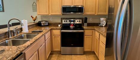 A modern kitchen with granite countertops, stainless steel appliances, and wooden cabinets.