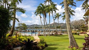 Un complexe hôtelier tropical doté d’une piscine, de palmiers et offrant une vue sur l’océan.