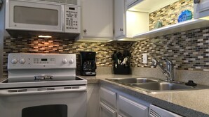 A kitchen with a white stove, a coffee maker, and a sink.