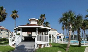 A gazebo with a white railing and a covered roof, surrounded by palm trees and a swimming pool. - "Koastal Escape" 1st Floor 1 BDR-1 Bath/Just steps to the Beach! (Corpus Christi)