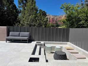 A patio with a sofa, two metal stools, and a woven ottoman. - Remodeled,2blocksWalkingDist From Main downtown/Activities/HotTub/BRAND NEW POOL (Sedona)