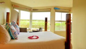 A hotel room with a large bed, a laptop on the desk, and a view of the outdoors. - Panoramic Windows, Double showers, Fireplace (Moss Landing)