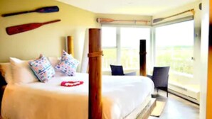 A bedroom with a large bed, pillows, a wooden post, and two baseball bats on the wall. - Panoramic Windows, Double showers, Fireplace (Moss Landing)
