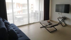 Ein modernes Wohnzimmer mit einer Couch, einem Couchtisch und einem Flachbildfernseher.