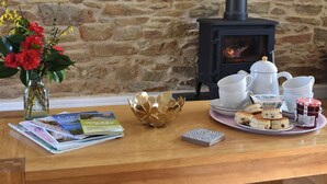 A wooden table with magazines, a vase of flowers, a decorative bowl, a tray with biscuits and jam, and a white kettle. - 3 bedroom accommodation in Mount Hawke, near St Agnes (Mount Hawke, near St Agnes)
