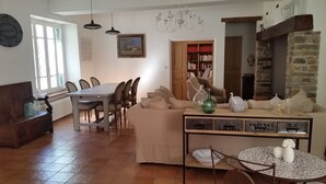 Een gezellige woonkamer met een eethoek, een open haard en een boekenkast.