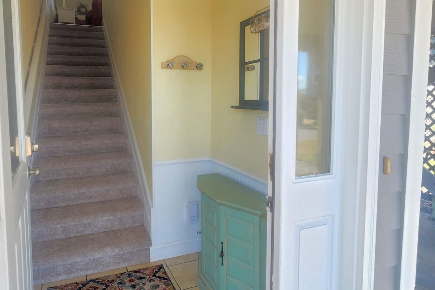 A staircase leading to a room with a teal cabinet and a mirror above the door.