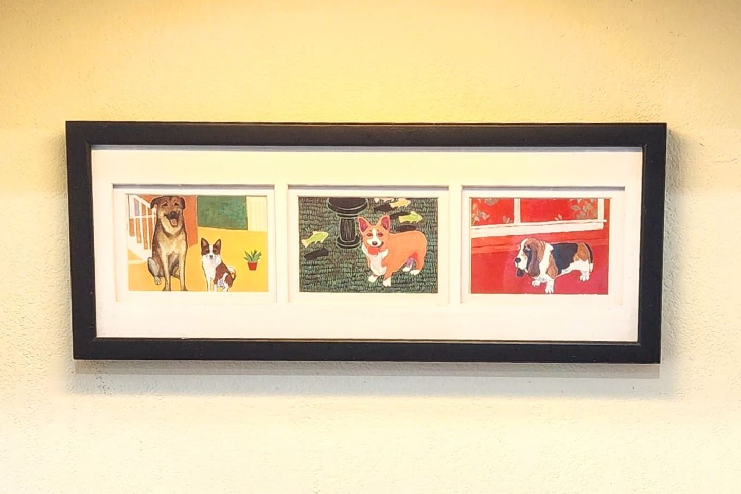 A framed artwork with three panels, each depicting a different dog in a distinct setting.