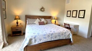 A bedroom with a wooden bed, two bedside tables with lamps, a ceiling fan, and a desk with chairs. - Dog-Friendly·Gulf Views· Steps to White Sand Beach (Port Saint Joe)