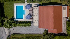 Luchtbeeld van een pand met een zwembad, ligbedden en parasols.