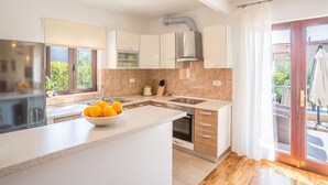 Een moderne keuken met een centraal eiland, een inbouwoven en uitzicht naar buiten.