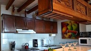 Una cocina con armarios de madera, estufa a gas, microondas y un cuadro de frutas en la pared.