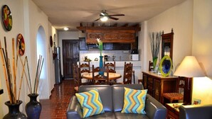 Una sala de estar con un sofá de cuero negro, dos jarrones azules y una concha decorativa sobre una mesa.