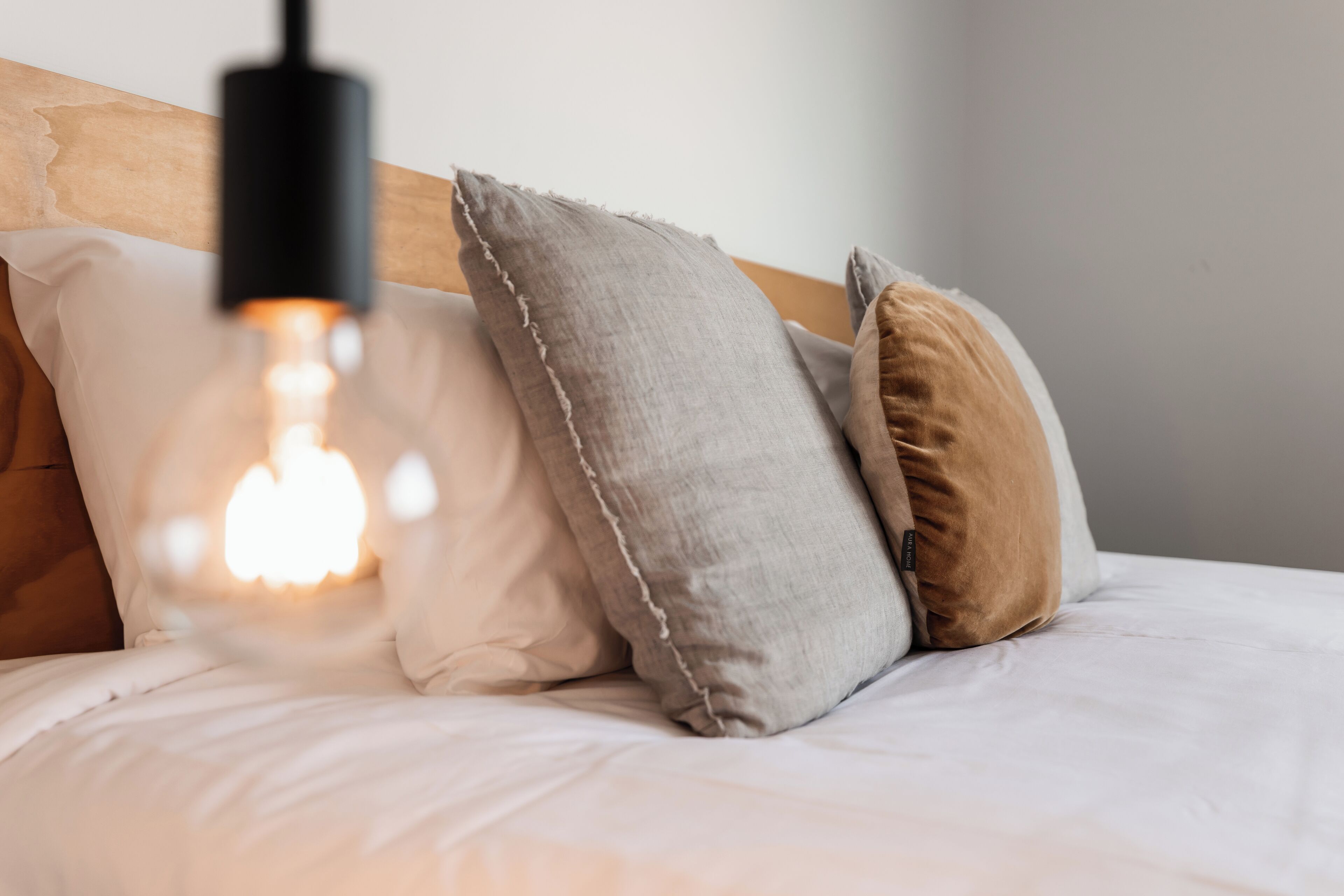 A bed with white bedding and multiple pillows in various colors.