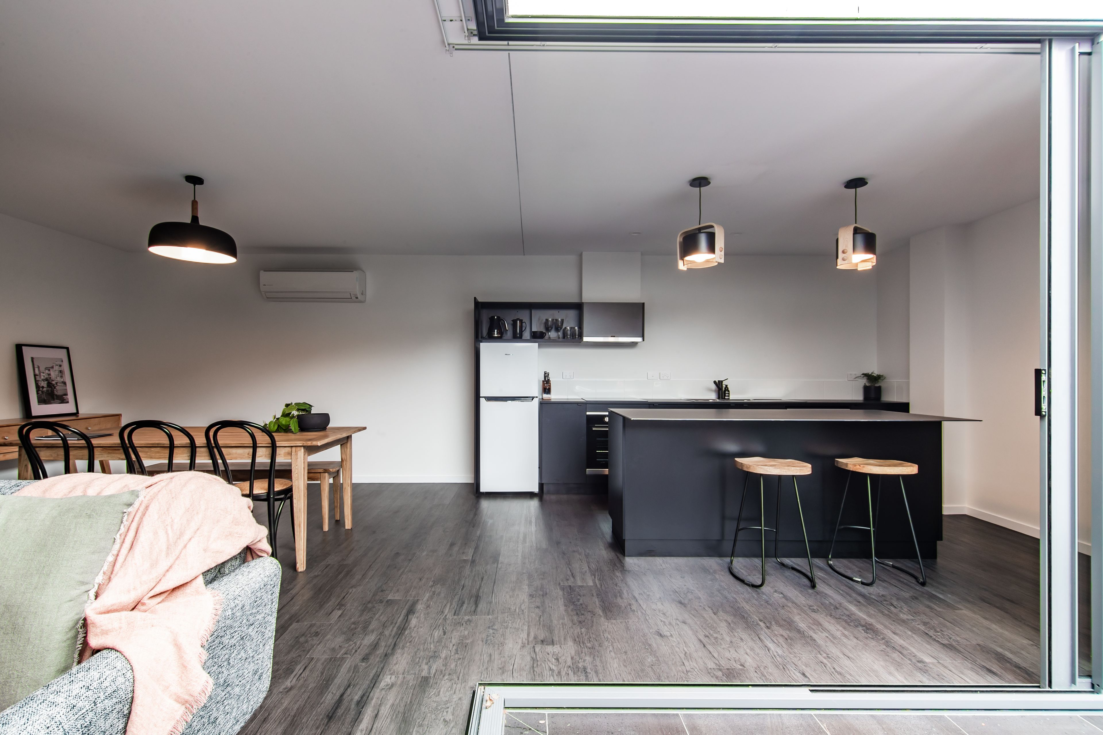 A modern kitchen with a central island, bar stools, and pendant lighting.