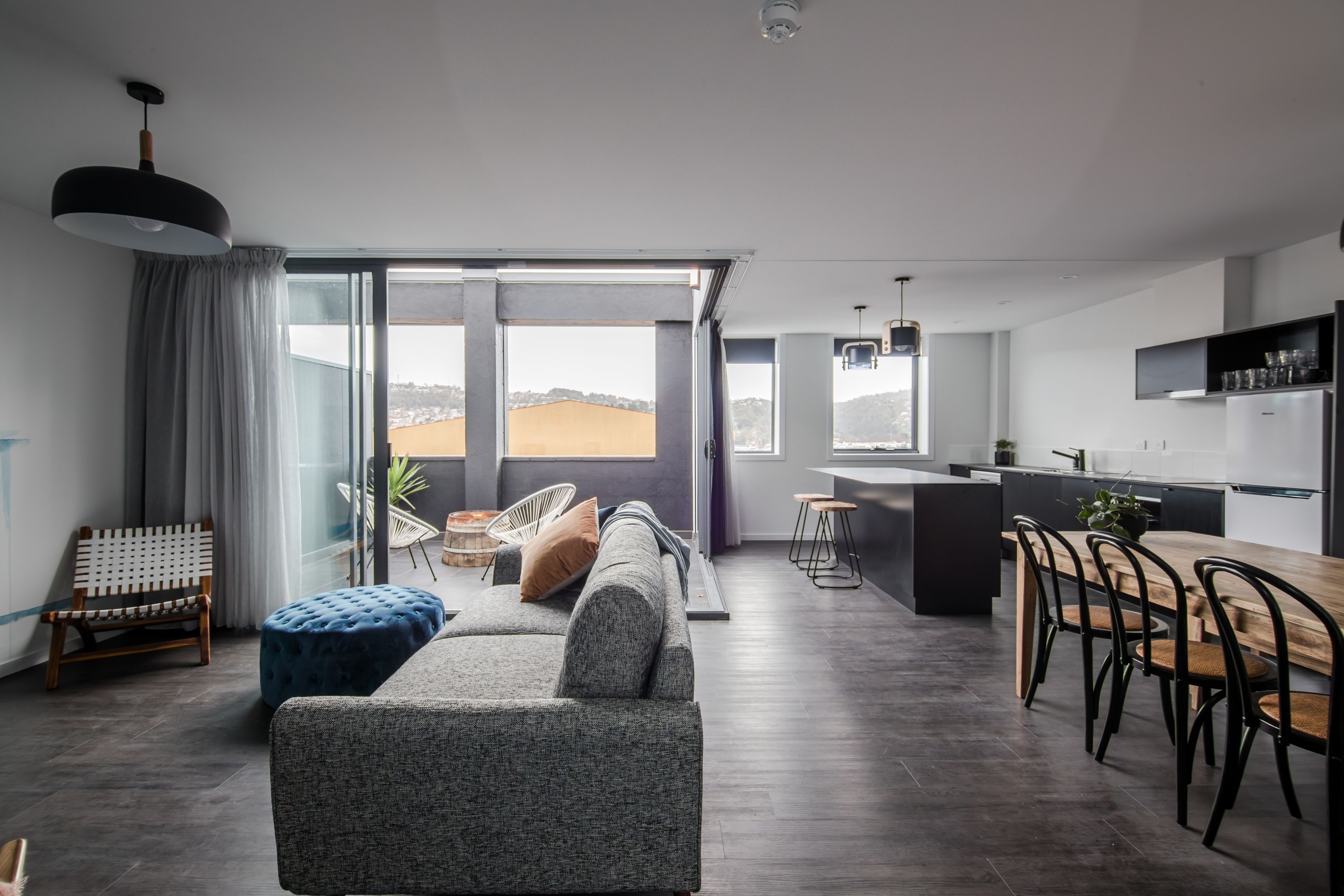 A modern living room with a sofa, ottoman, and dining area with chairs.