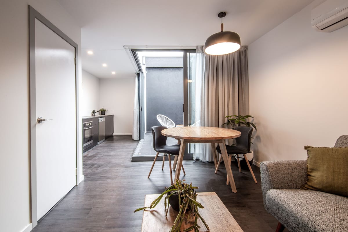 Una sala de estar moderna con comedor, un sofá, una mesa de centro y una planta.