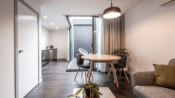 A modern living room with a dining area, a sofa, a coffee table, and a plant.