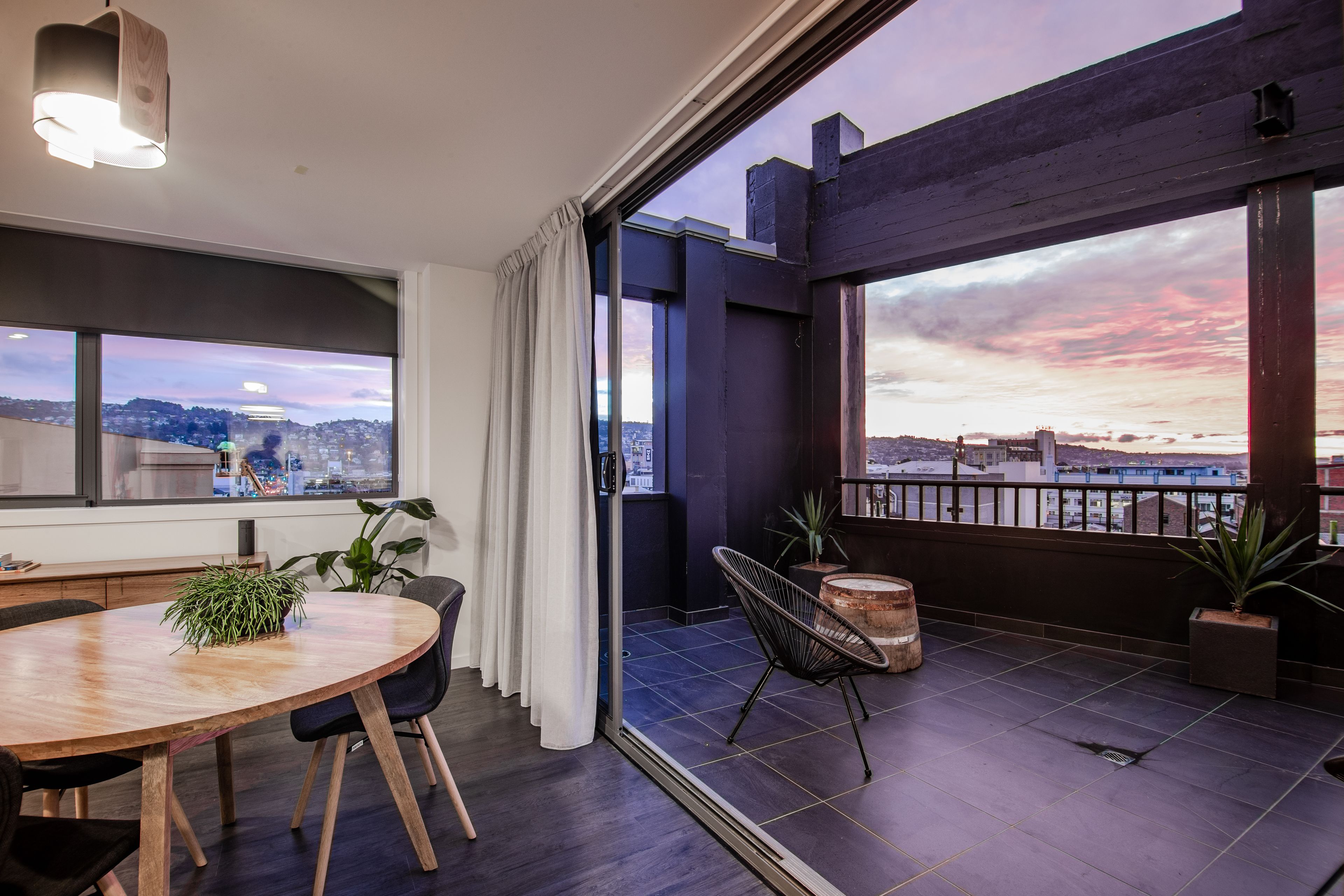 Un salon moderne doté d’une grande fenêtre, d’un coin repas et d’un balcon offrant une vue sur la ville.