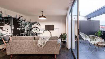 A modern living room with a sofa, a TV, and a dining area.