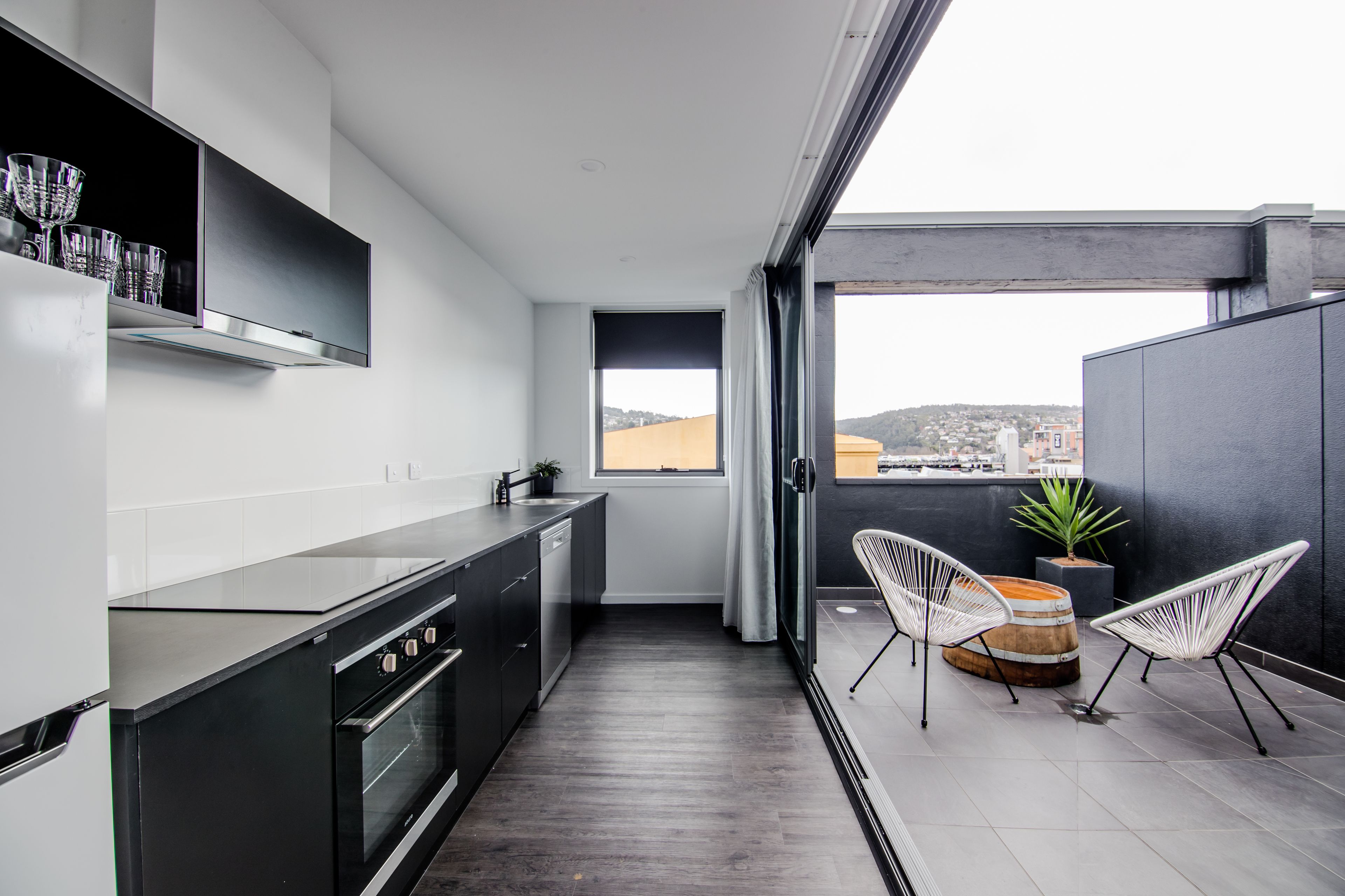 A modern kitchen with a view of the city, a dining area with chairs, and a small table.