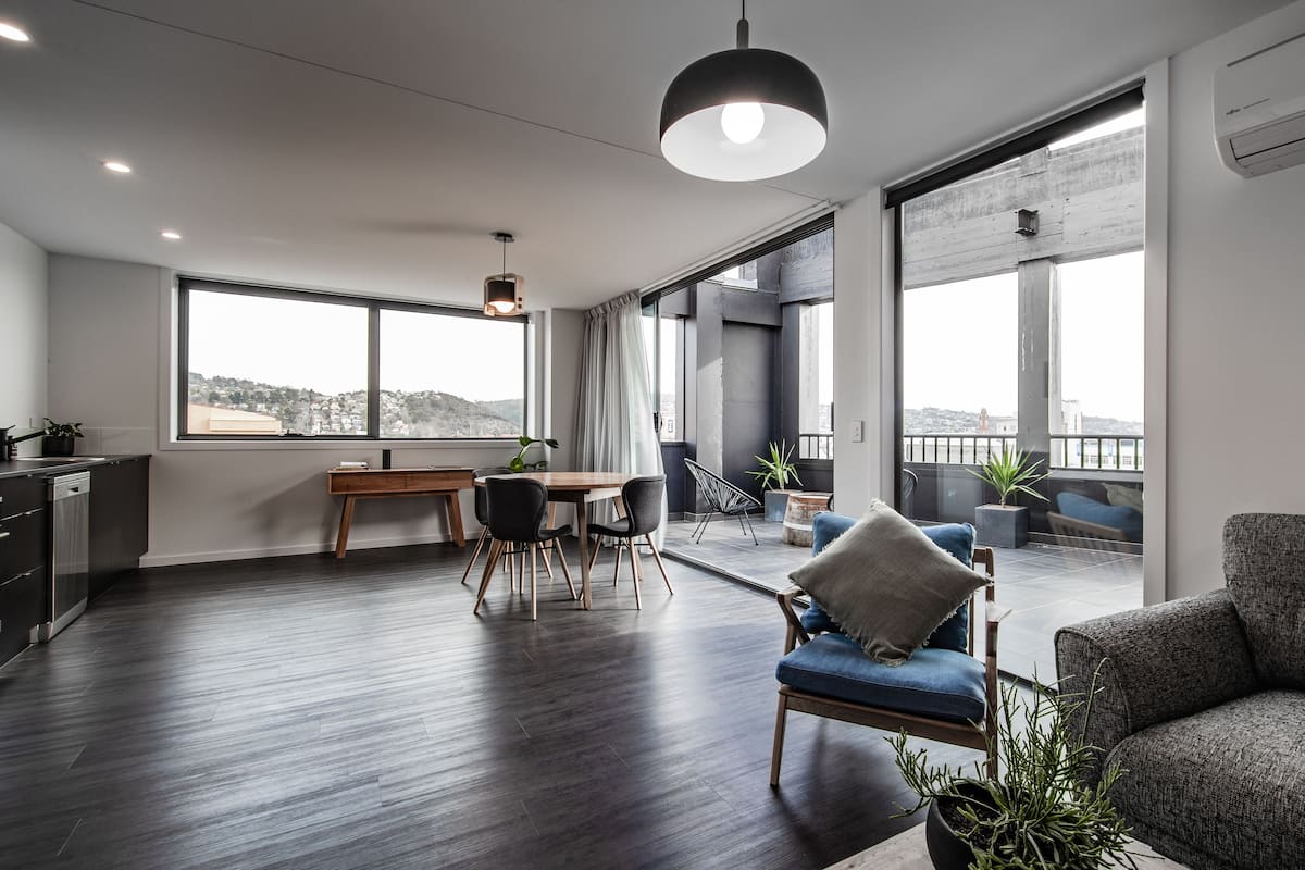 Un espacio habitable moderno con comedor, sofá y balcón con vista a la ciudad.