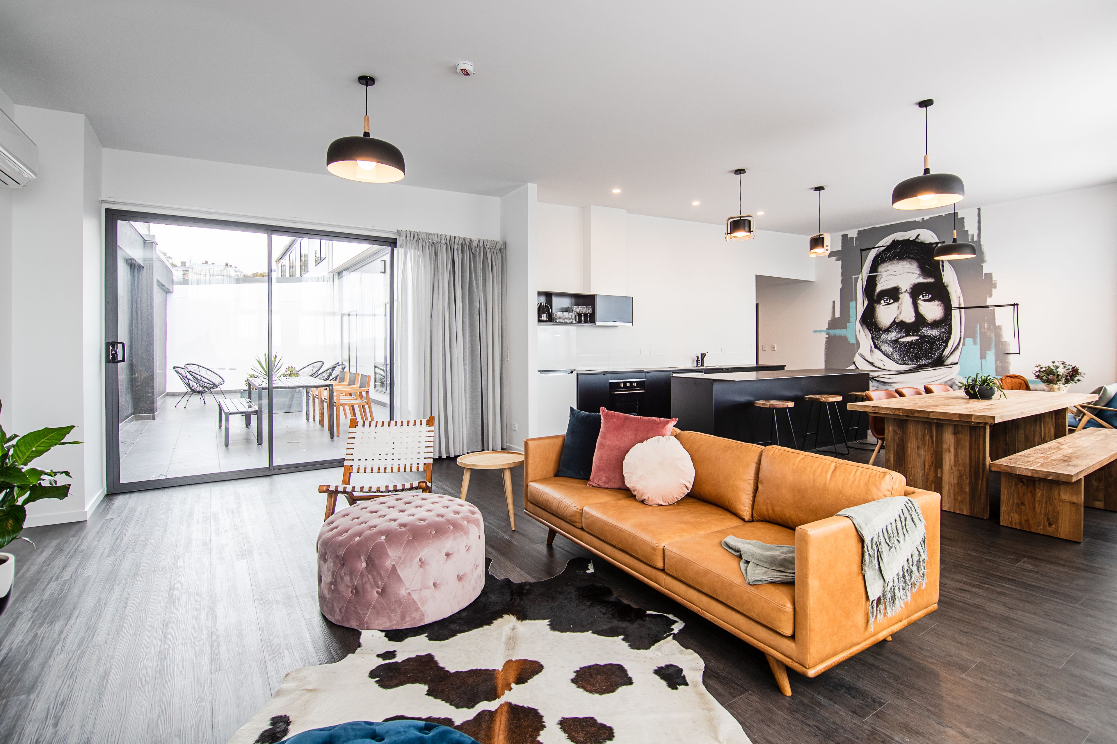 A modern living room with a sofa, ottoman, and a cowhide rug.