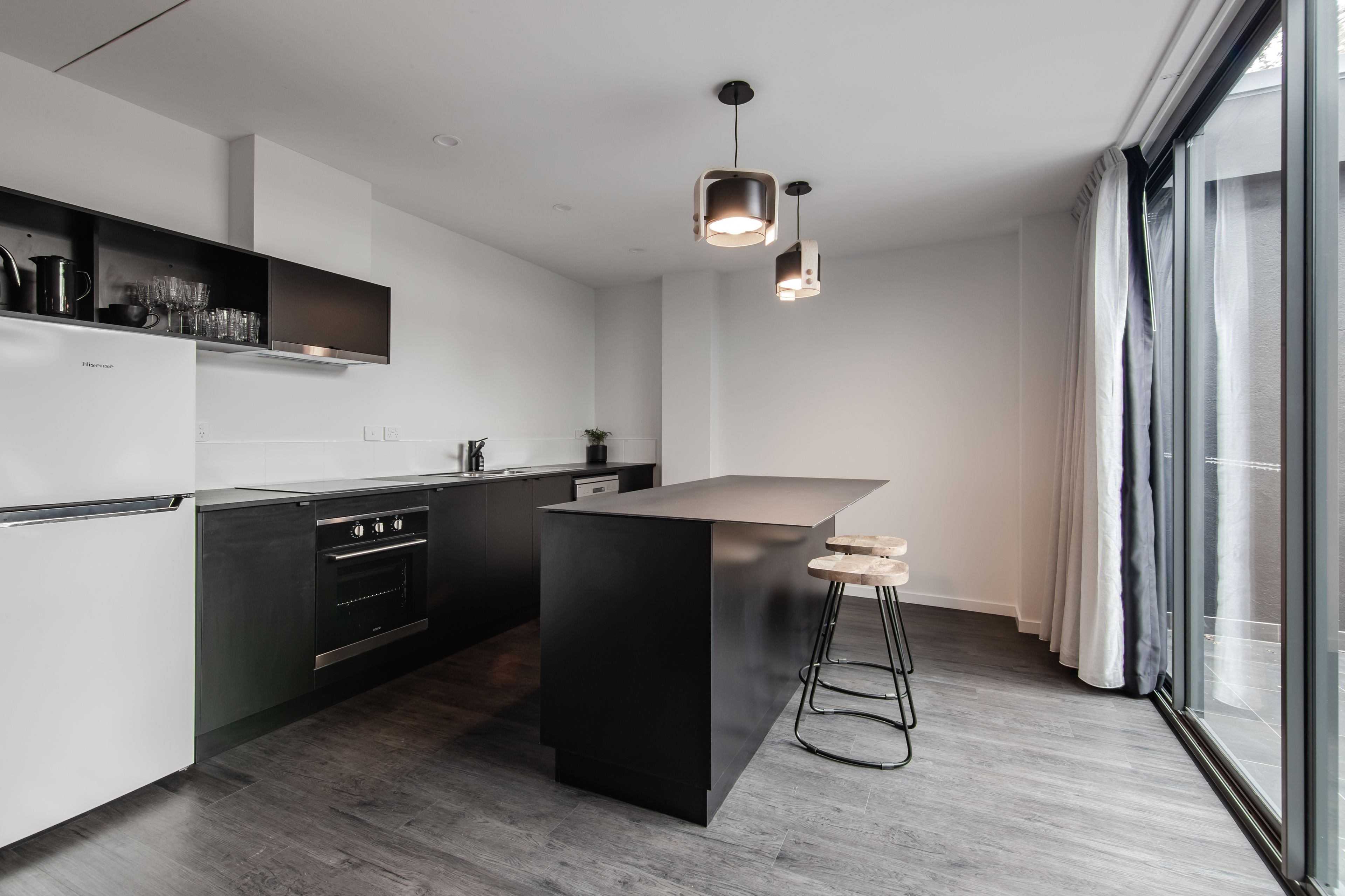 Una cocina moderna con una isla central, electrodomésticos de acero inoxidable e iluminación colgante.