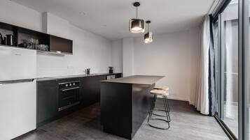 Una cocina moderna con una isla central, electrodomésticos de acero inoxidable e iluminación colgante.