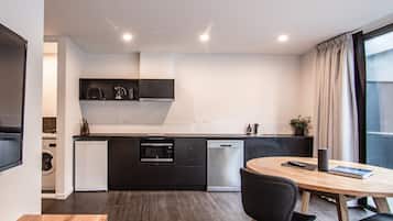 A modern kitchen with built-in appliances, a dining area with a wooden table and chairs, and a large window with curtains.