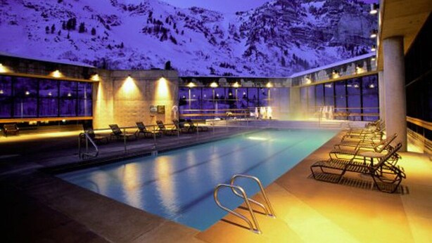 A pool area with lounge chairs and a view of snow-covered mountains at dusk.