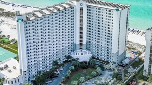 Un hotel grande de varios pisos con un patio central, rodeado por una playa y el océano.