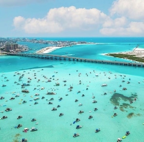 An aerial view of a coastal area with numerous boats, a bridge, and a cityscape in the background.